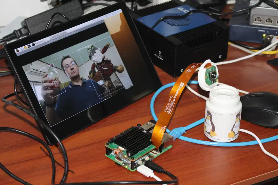 YOLOv8 object detection running on the Hailo-10H, with bounding boxes drawn around a person and nearby objects in the live camera feed
