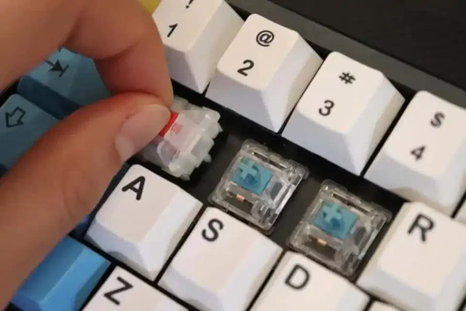 Installing a new mechanical switch into a hotswap socket on a keyboard PCB, pressing straight down to align pins
