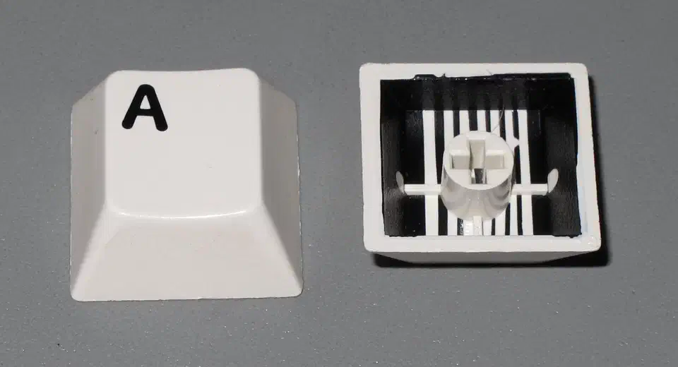 Underside view of two-shot injection molded keycaps showing the separate legend plastic fused into each cap