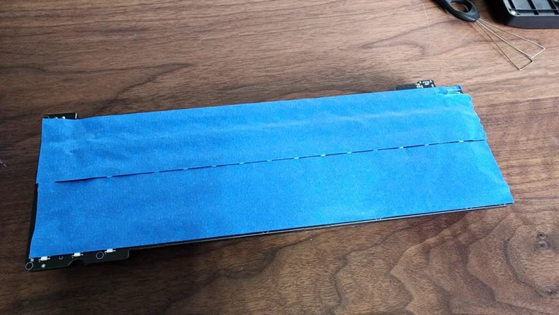 Layers of painter&rsquo;s tape applied to the back of a keyboard PCB for the Tempest tape mod