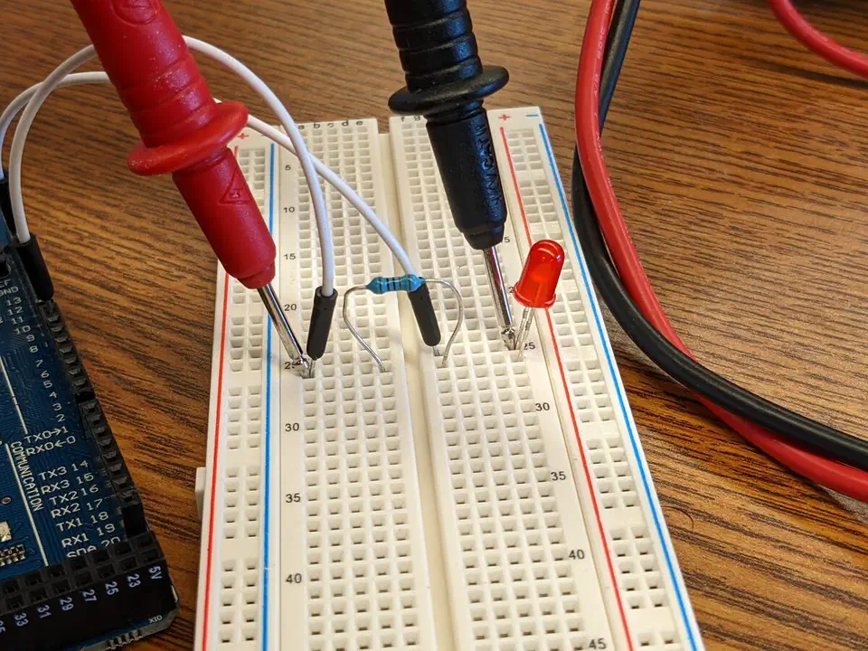 Multimeter probes touching a breadboard circuit
